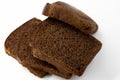 Several sliced Ã¢â¬â¹Ã¢â¬â¹pieces of brown rye natural organic bread lie on top of each other on a white background close-up